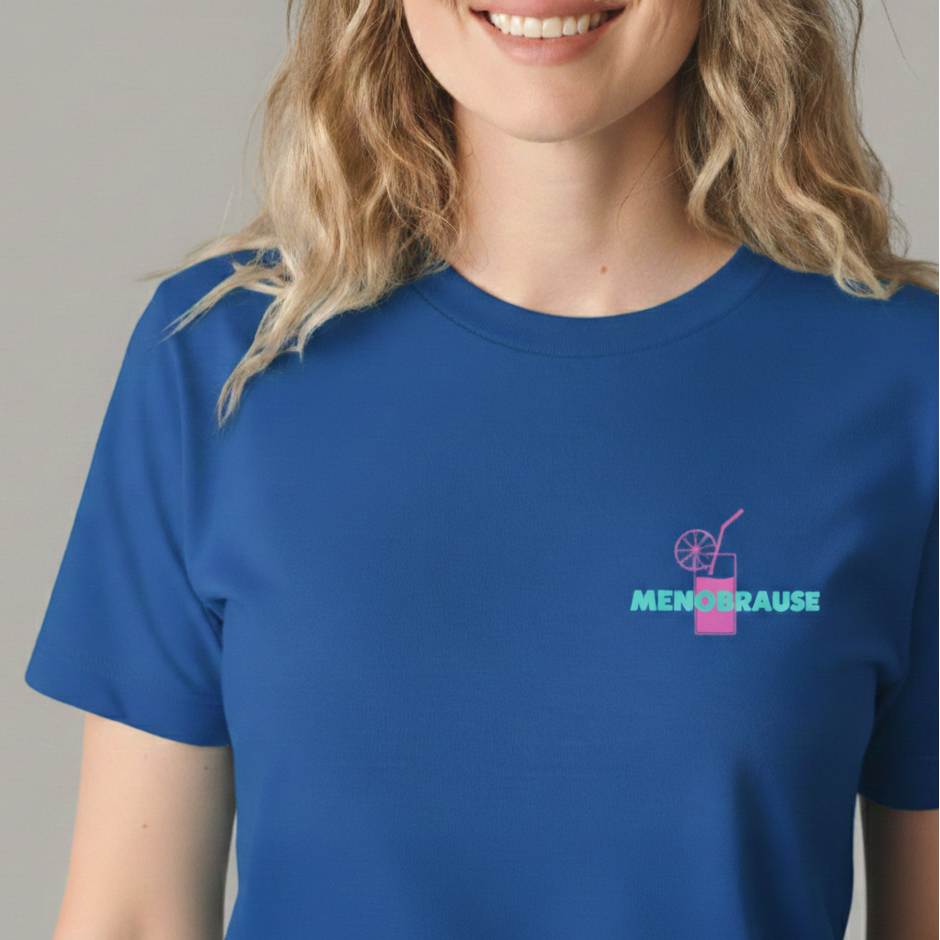 Kräftig blaues Damen T-Shirt mit einem kleinen, mittigen Aufdruck auf der Brust. Das Design zeigt das Wort 'MENOBRAUSE' in Türkis und ein pinkes Erfrischungsgetränk mit Zitrone und Strohhalm was von einer blonden Frau getragen wird.