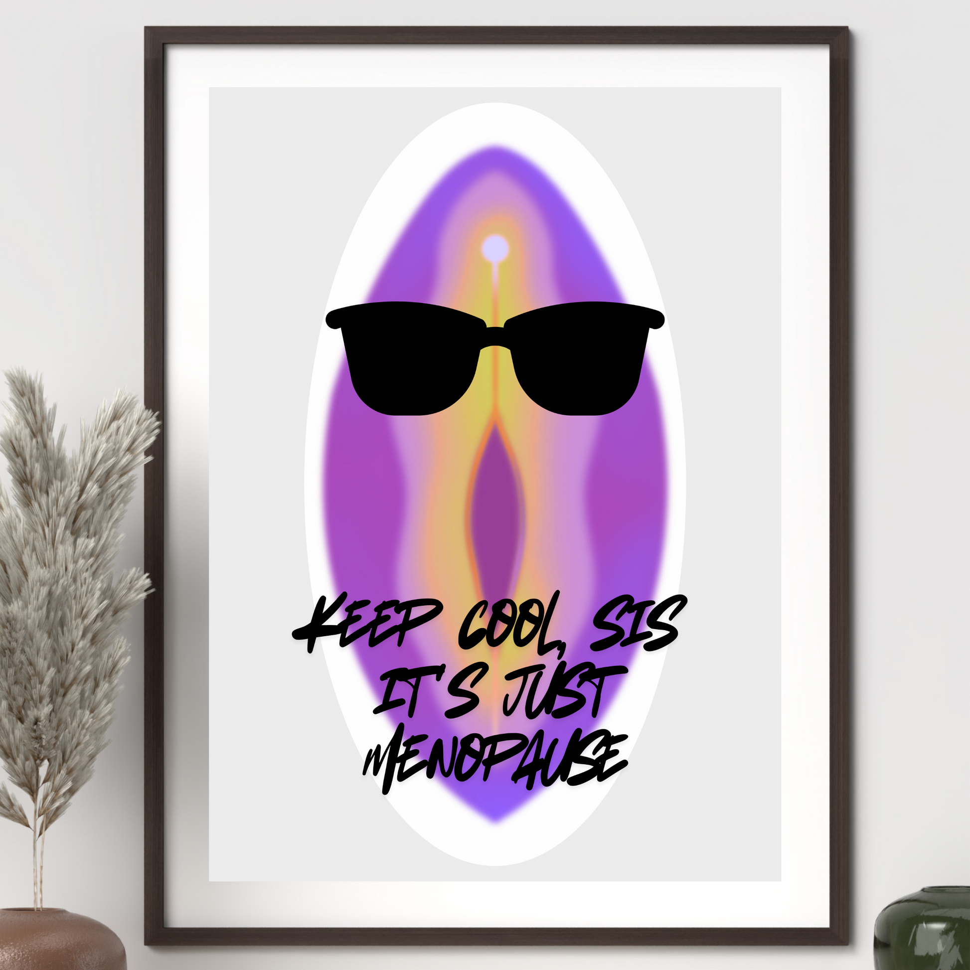 Modernes Grafik-Poster auf weißem Hintergrund mit mit abstrakten, lila-gelben Form (Symbolik der Vulva), die eine schwarze Sonnenbrille trägt. Darunter steht in schwarzer Schreibschrift der Text: „KEEP COOL, SIS IT'S JUST MENOPAUSE“ was in einem schwarzen Rahmen über einem Sideboard hängt. Hochformat, Glanz Finish