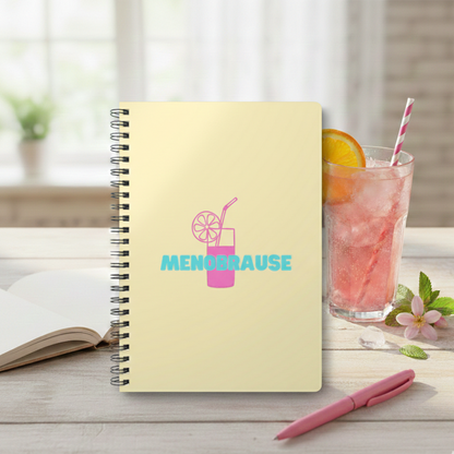Gelbes A5 Spiralnotizbuch mit der Aufschrift 'MENOBRAUSE' in blauer Schrift und einer pinken Illustration eines Erfrischungsgetränks mit Strohhalm und Zitrone. Lustiges Journal-Design für Frauen in den Wechseljahren,was von einem Glas mit Strohalm und hinter einem rosa Kugelschreiber steht