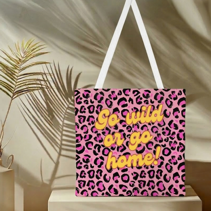 Stylische Stofftasche mit auffälligem pink-schwarzem Leopardenmuster. In der Mitte steht der gelbe Schriftzug 'Go wild or go home!' in einer verspielten Schriftart. Die Tasche hat weiße Tragehenkel und ist vor einem hellen Hintergrund freigestellt.