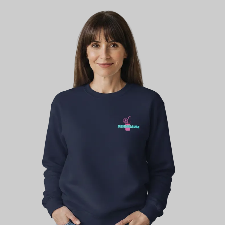 Dunkelblaues (Navy) Damen-Sweatshirt mit einem kleinen Print auf der linken Brust für die Menopause. Das Motiv zeigt ein pinkes Cocktailglas mit Strohhalm und Zitronenscheibe, über dem steht in türkiser das Wort 'MENOBRAUSE' was von einer dunkelhaarigen Frau getragen wird.
