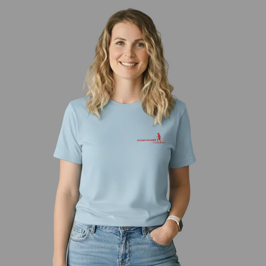 Hellblaues Damen T-Shirt aus Baumwolle mit einem kleinen roten Aufdruck auf der linken Brust. Das Motiv zeigt eine Surferin auf einem Board und den Schriftzug 'HITZEWELLENREITERIN' in moderner, sportlicher Schrift was von einer blonden Frau getragen wird.