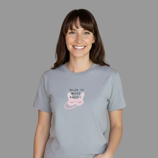 Meliertes graues Damen T-Shirt mit einem mittigen Brustprint. Das Motiv zeigt den Text 'Heute is Mutti kaputti' in Schreibmaschinenschrift über einer illustrierten rosa Schlafmaske mit geschlossenen Augen was von einer dunkelhaarigen Frau getragen wird.