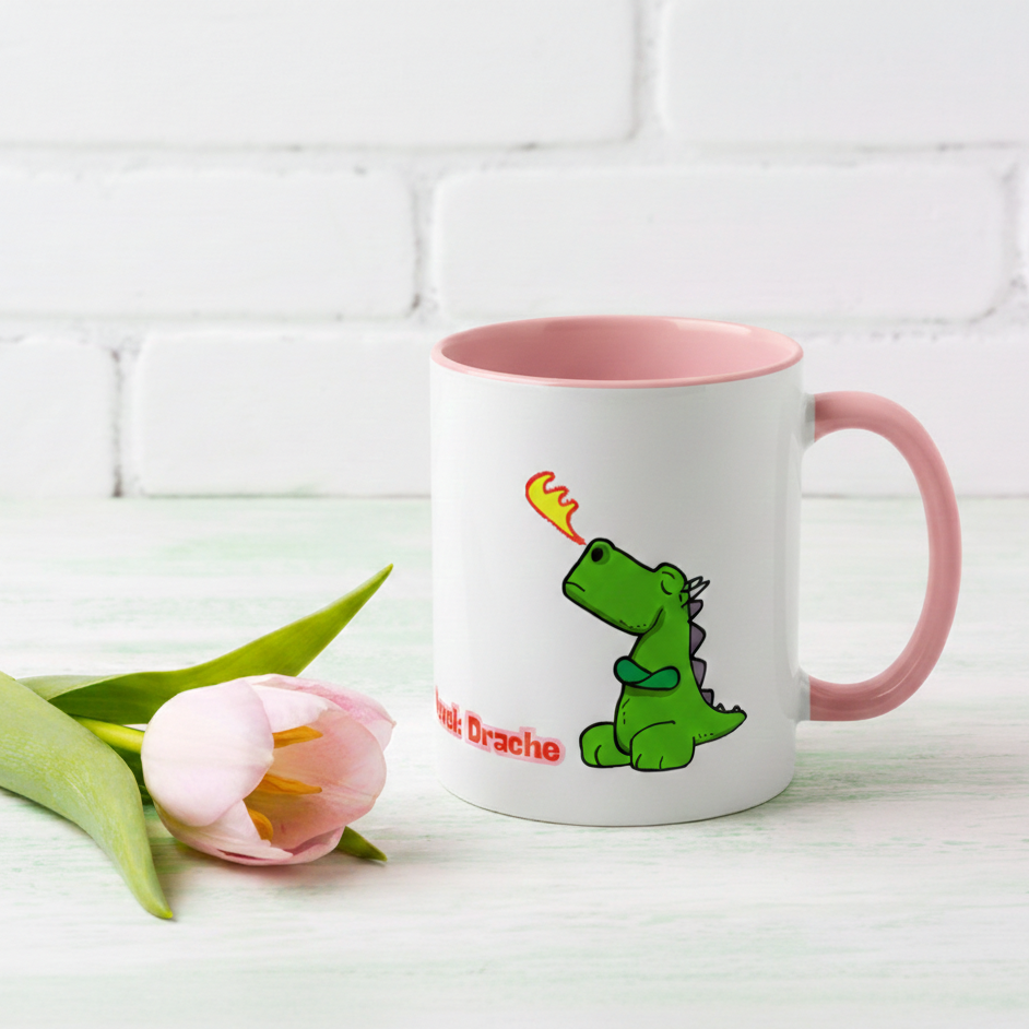 Weiße Keramiktasse mit rosa Henkel und Innenseite, illustriert mit einem kleinen grünen Drachen, der Feuer speit, und dem pinken Schriftzug „Hormonlevel: Drache“.